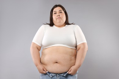 Photo of Woman with excessive belly fat on grey background. Overweight problem