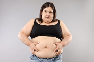 Photo of Woman with excessive belly fat on grey background. Overweight problem