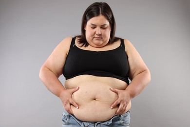 Photo of Woman with excessive belly fat on grey background. Overweight problem