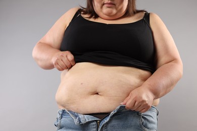 Photo of Woman with excessive belly fat on grey background, closeup. Overweight problem