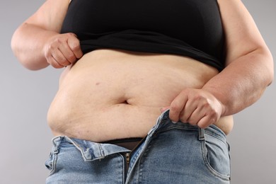 Photo of Woman with excessive belly fat on grey background, closeup. Overweight problem