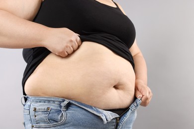 Photo of Woman with excessive belly fat on grey background, closeup