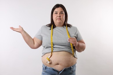 Photo of Overweight woman with measuring tape on white background