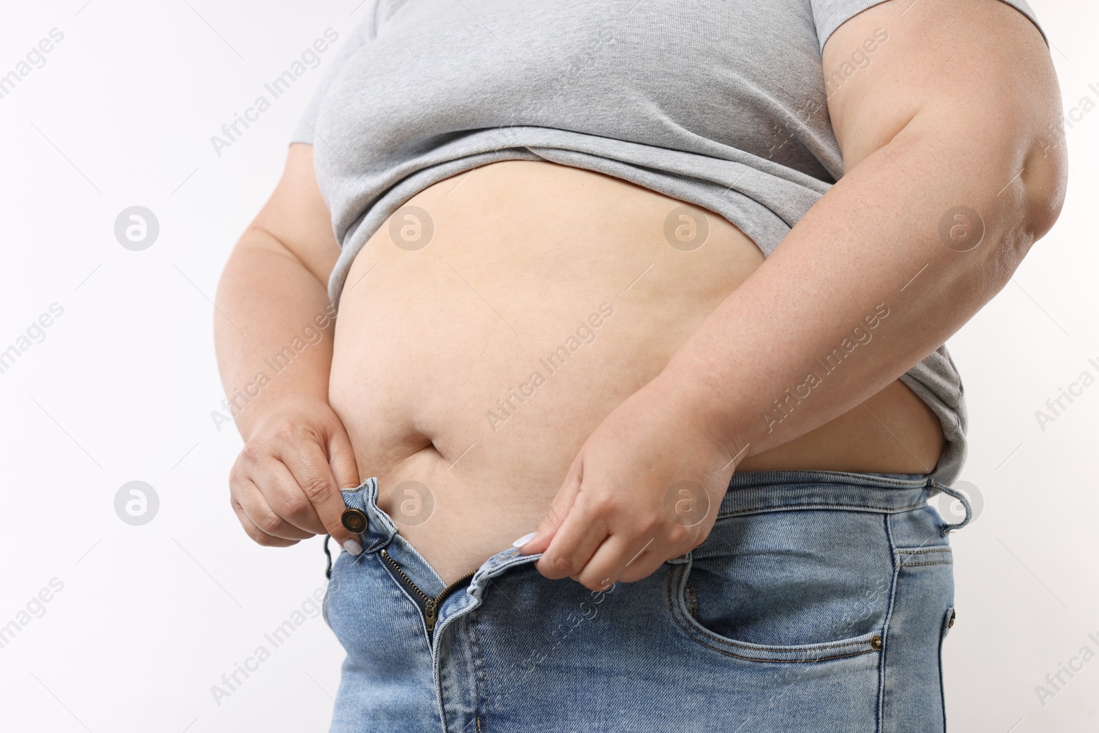 Overweight woman trying to put on tight jeans against white background, closeup Photo of Overweight woman trying to put on tight jeans against white background, closeup