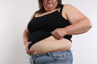 Photo of Woman with excessive belly fat on white background, closeup