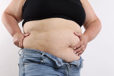 Photo of Woman with excessive belly fat on white background, closeup