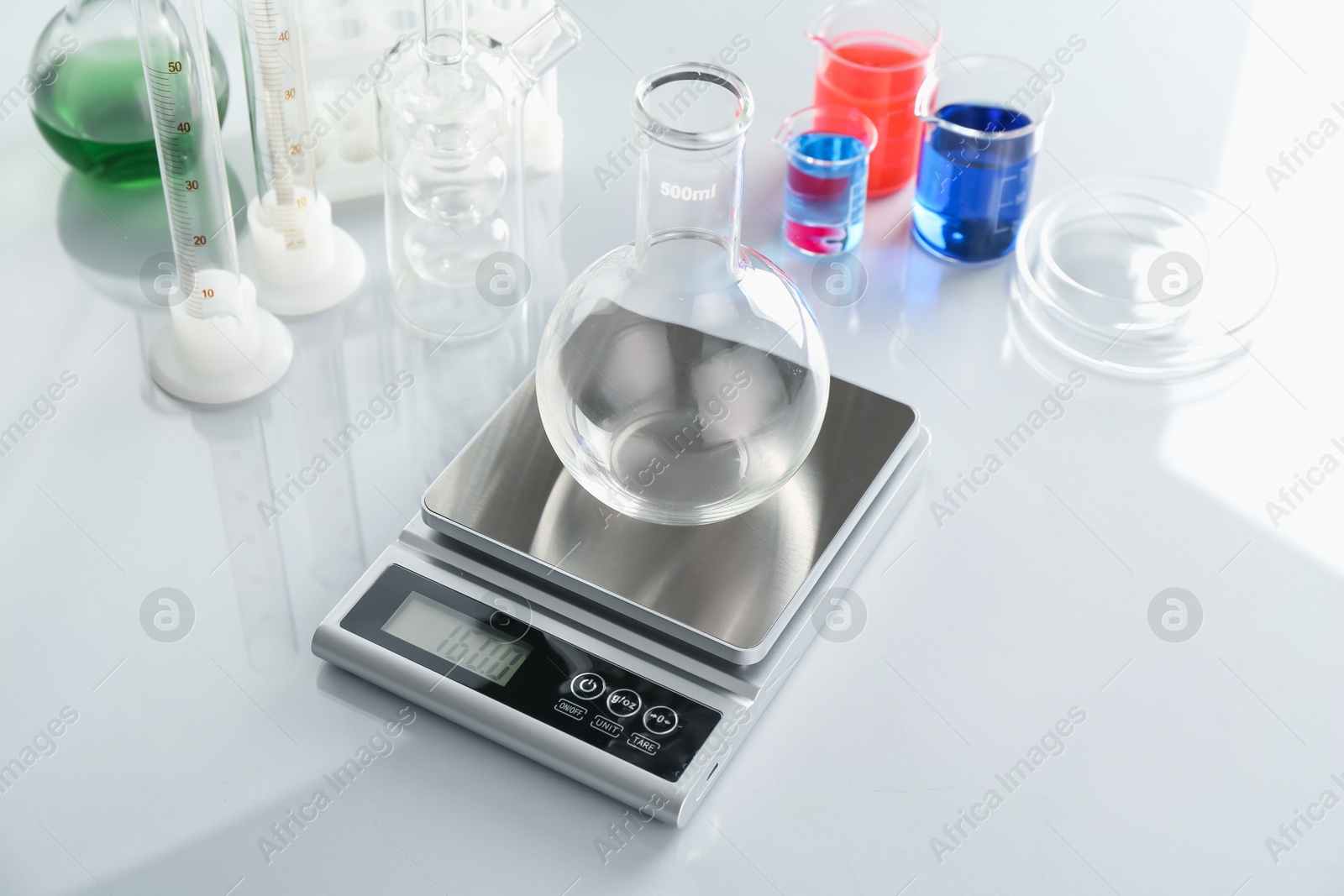 Scale with empty flask and other laboratory glassware on white mirror table Photo of Scale with empty flask and other laboratory glassware on white mirror table