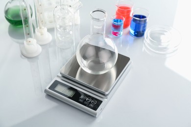 Photo of Scale with empty flask and other laboratory glassware on white mirror table