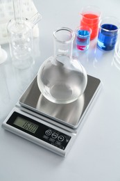 Photo of Scale with empty flask and other laboratory glassware on white mirror table