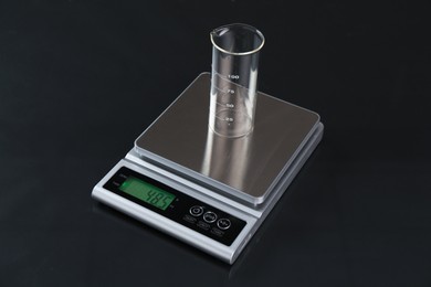 Photo of Scale with empty beaker on black mirror table, closeup