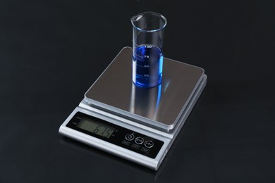 Photo of Scale with beaker of sample on black mirror table, closeup