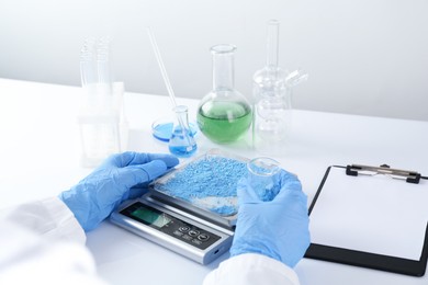 Photo of Scientist weighing sample on scales at white table, closeup