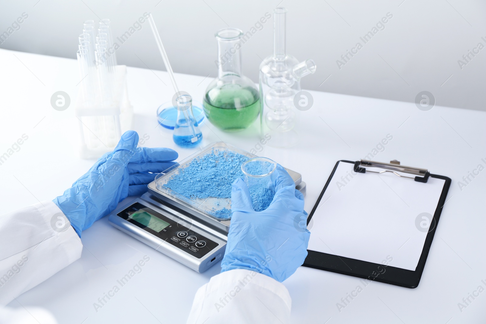 Scientist weighing sample on scales at white table, closeup Photo of Scientist weighing sample on scales at white table, closeup