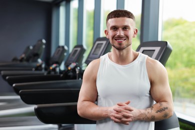 Photo of Portrait of professional personal trainer in sport center. Space for text