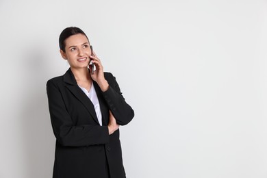 Photo of Confident business woman in suit with smartphone on light background. Space for text