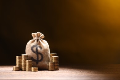 Photo of Bag with dollar sign and stacked coins on table against dark color gradient background, space for text