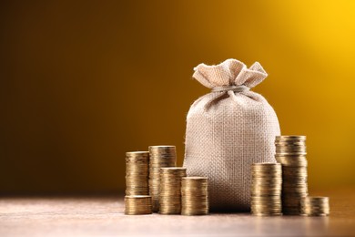 Photo of Bag and stacked coins on table against dark yellow gradient background, space for text