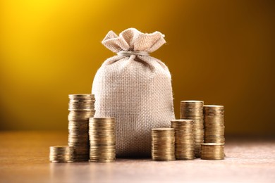 Photo of Bag and stacked coins on table against dark yellow gradient background