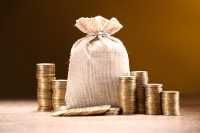 Photo of Bag and stacked coins on table against color gradient background