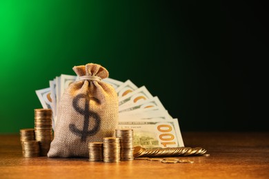 Photo of Bag, dollar banknotes and stacked coins on wooden table against green gradient background
