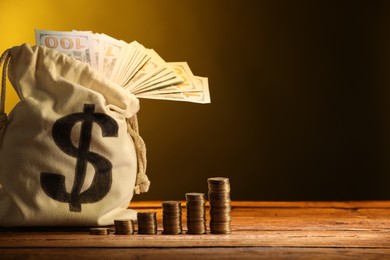 Photo of Bag with dollar banknotes and stacked coins on wooden table against yellow gradient background, space for text