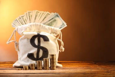Photo of Bag with dollar banknotes and stacked coins on wooden table against brown gradient background, space for text