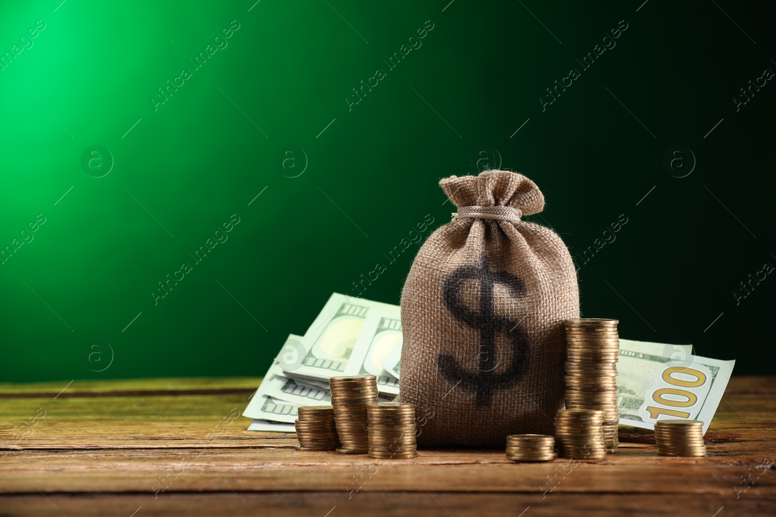 Bag, dollar banknotes and stacked coins on wooden table against green gradient background, space for text Photo of Bag, dollar banknotes and stacked coins on wooden table against green gradient background, space for text