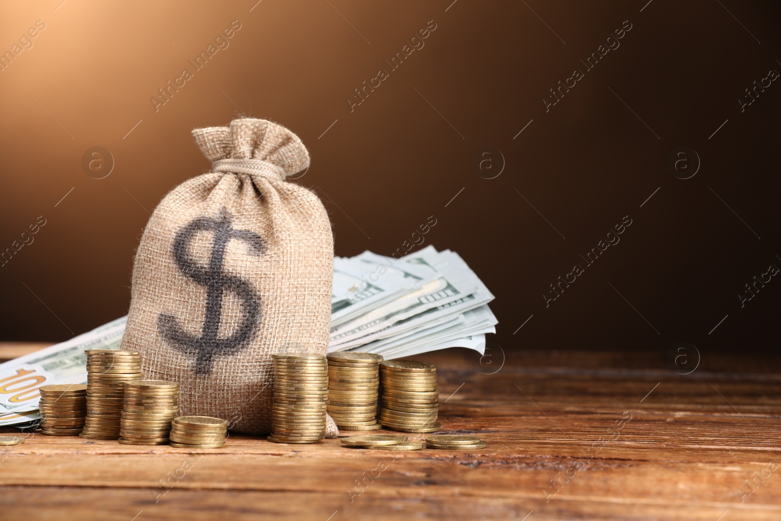 Bag, dollar banknotes and stacked coins on wooden table against beige gradient background, space for text Photo of Bag, dollar banknotes and stacked coins on wooden table against beige gradient background, space for text