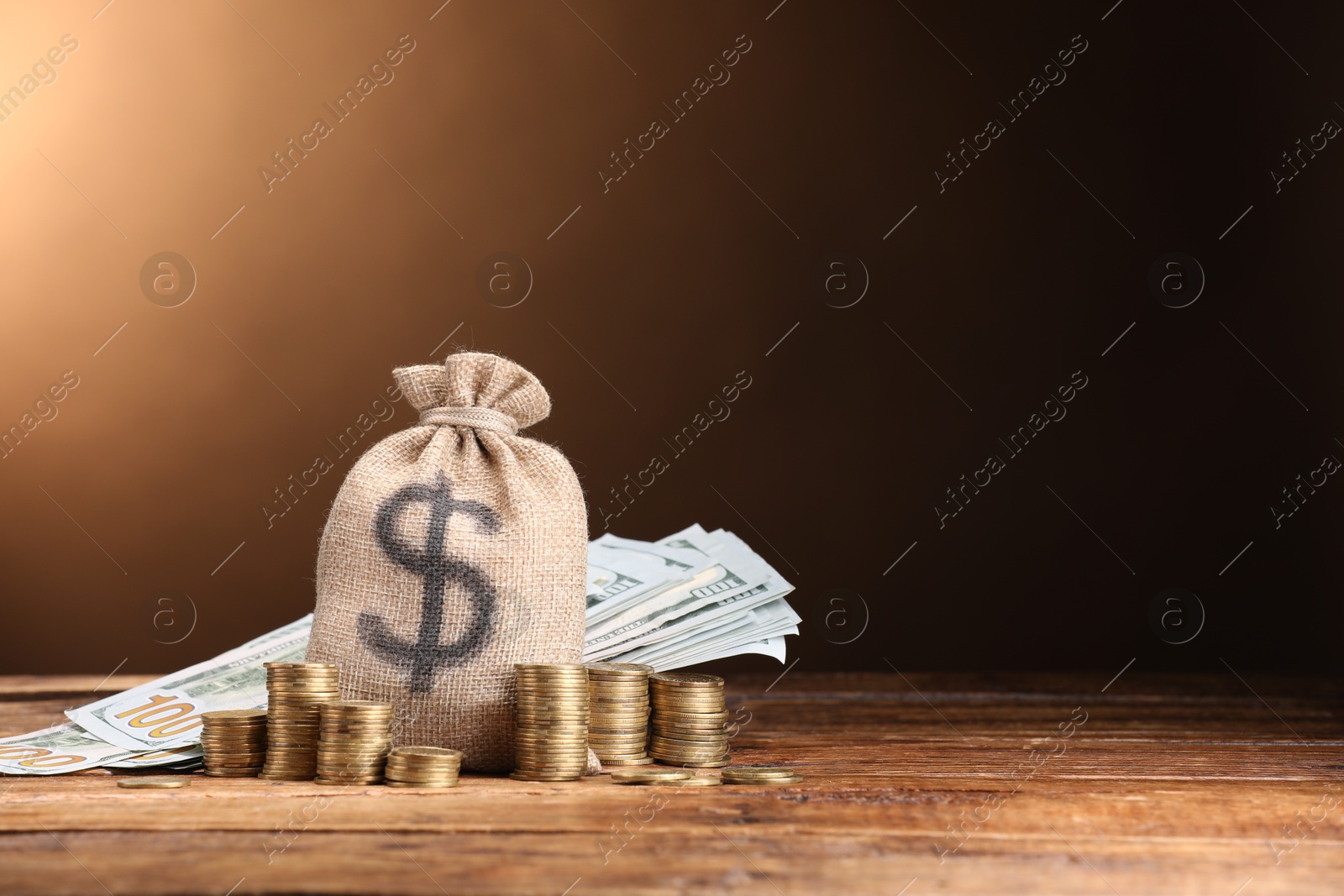 Bag, dollar banknotes and stacked coins on wooden table against beige gradient background, space for text Photo of Bag, dollar banknotes and stacked coins on wooden table against beige gradient background, space for text