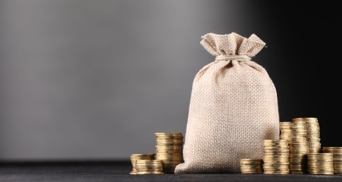 Photo of Bag and stacked coins on black table against gray gradient background, space for text
