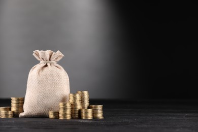Photo of Bag and stacked coins on black table against gray gradient background, space for text