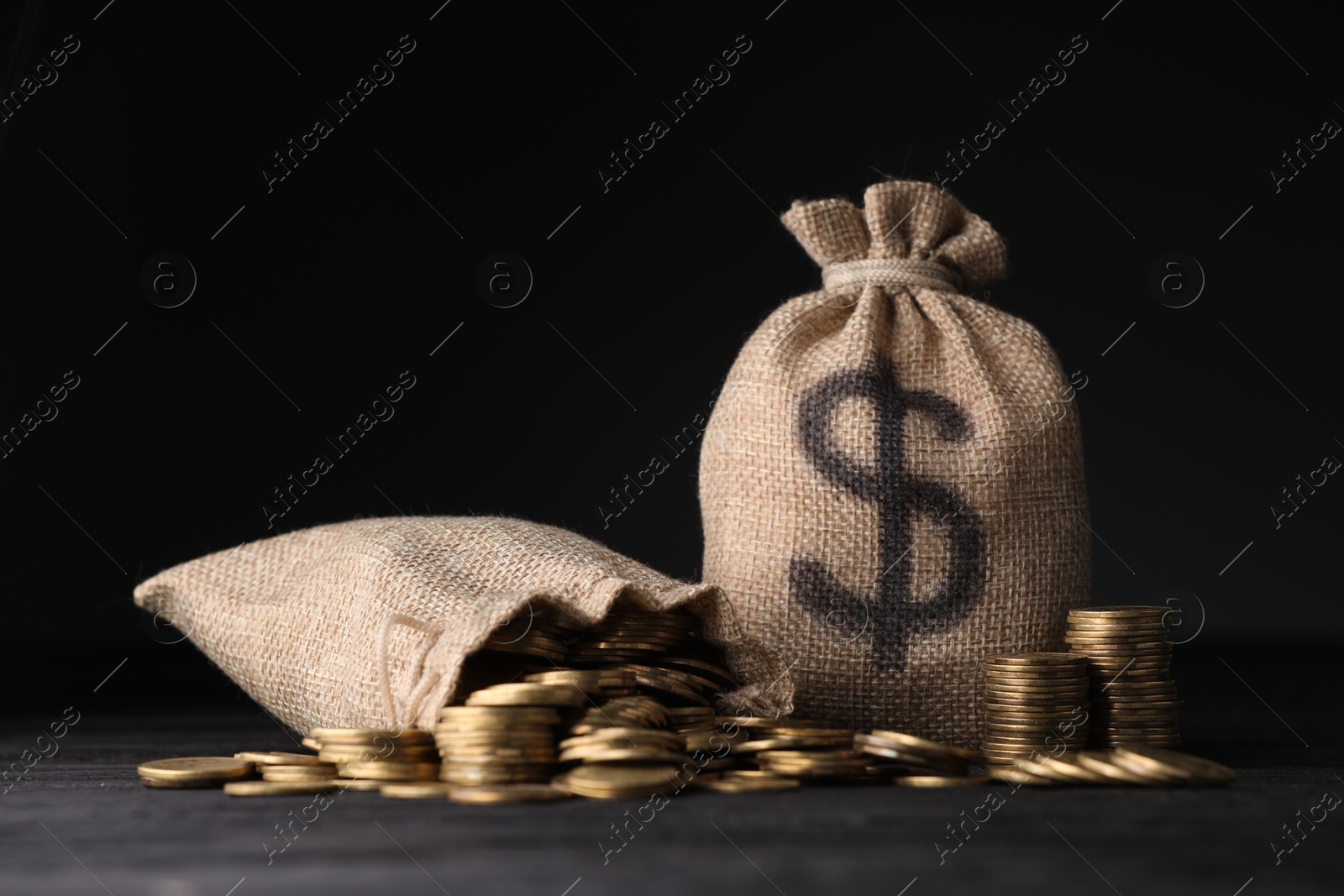 Bags with dollar sign and coins on dark background Photo of Bags with dollar sign and coins on dark background