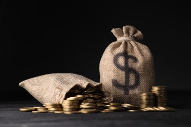Photo of Bags with dollar sign and coins on dark background