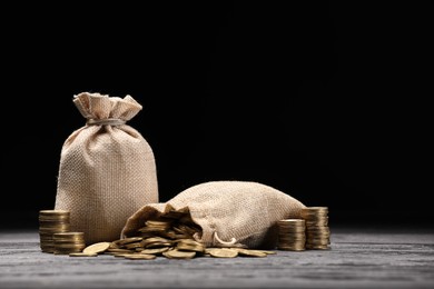 Photo of Bags and coins on gray wooden table against dark background