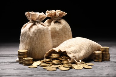 Photo of Bags and coins on gray wooden table against dark background