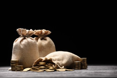 Photo of Bags and coins on gray table against dark background
