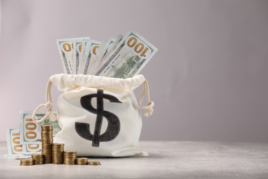 Photo of Bag with dollar banknotes and stacked coins on gray table textured against light background, space for text