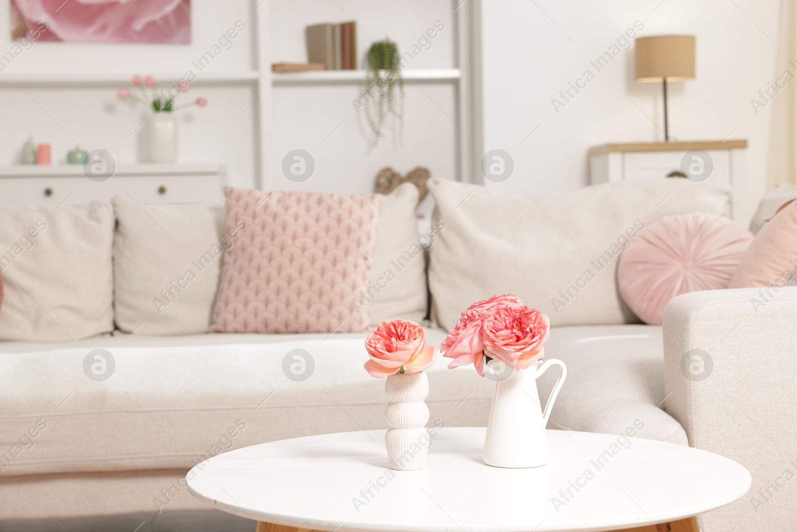 Cozy living room interior. Side table with flowers and soft sofa indoors Photo of Cozy living room interior. Side table with flowers and soft sofa indoors
