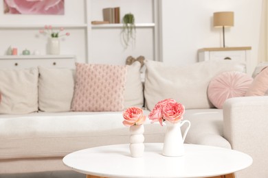 Photo of Cozy living room interior. Side table with flowers and soft sofa indoors