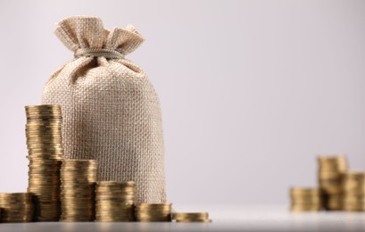 Photo of Bag and stacked coins on light background, selective focus. Space for text