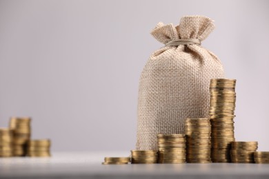 Photo of Bag and stacked coins on light background, selective focus. Space for text