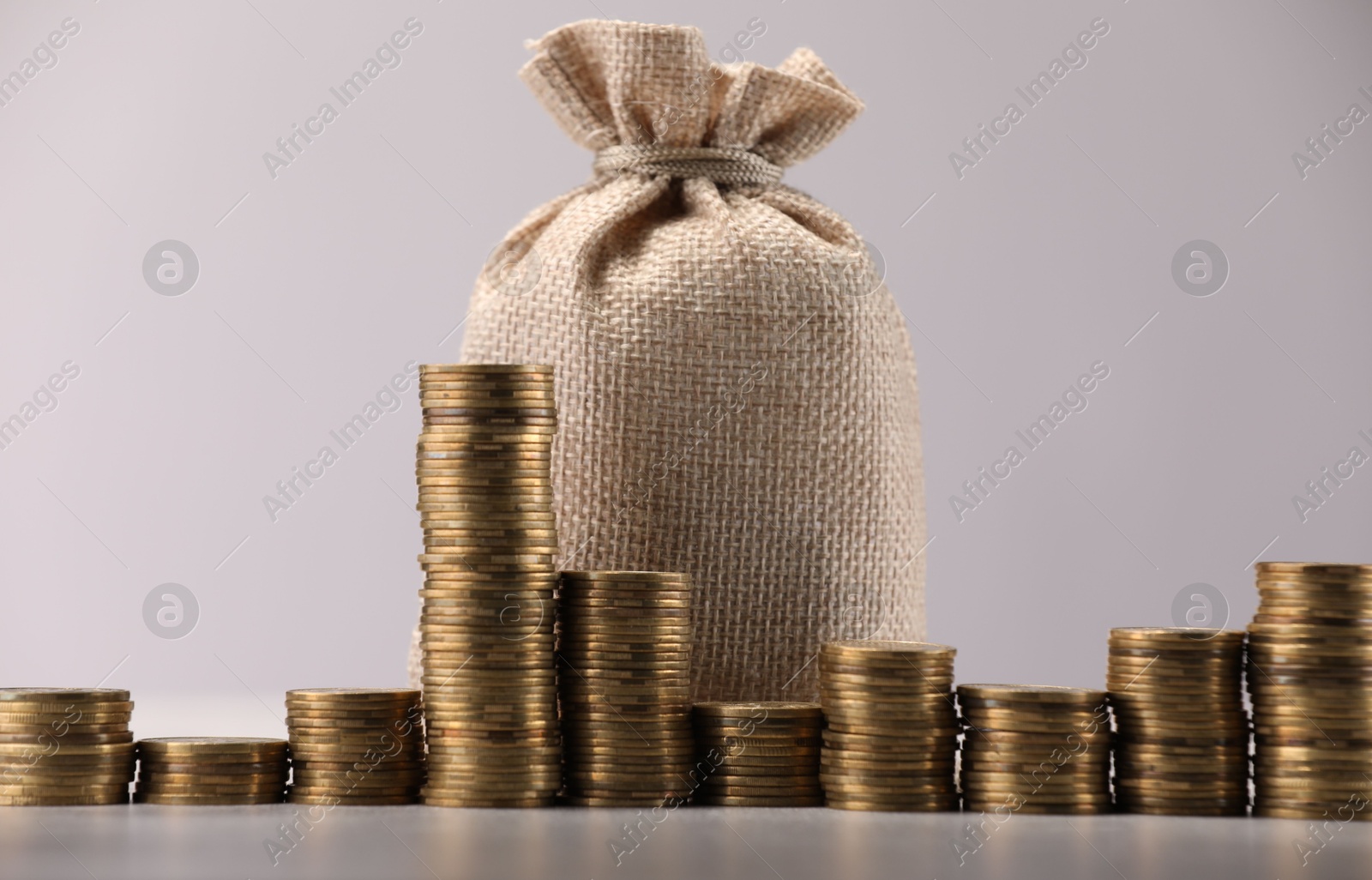 Bag and stacked coins on light background Photo of Bag and stacked coins on light background