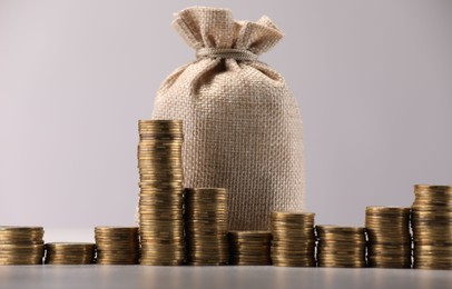 Photo of Bag and stacked coins on light background