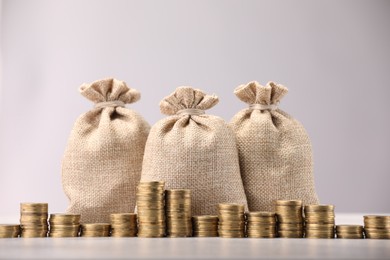 Photo of Bags and stacked coins on light background