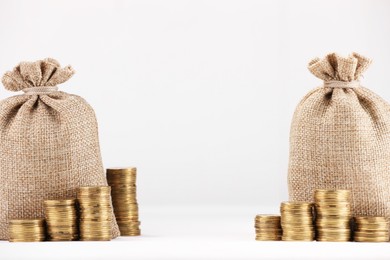 Photo of Bags and stacked coins on white background, space for text