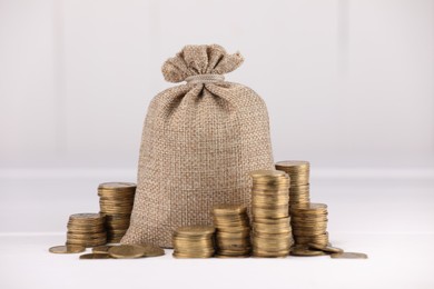 Photo of Bag and stacked coins on white table against light background