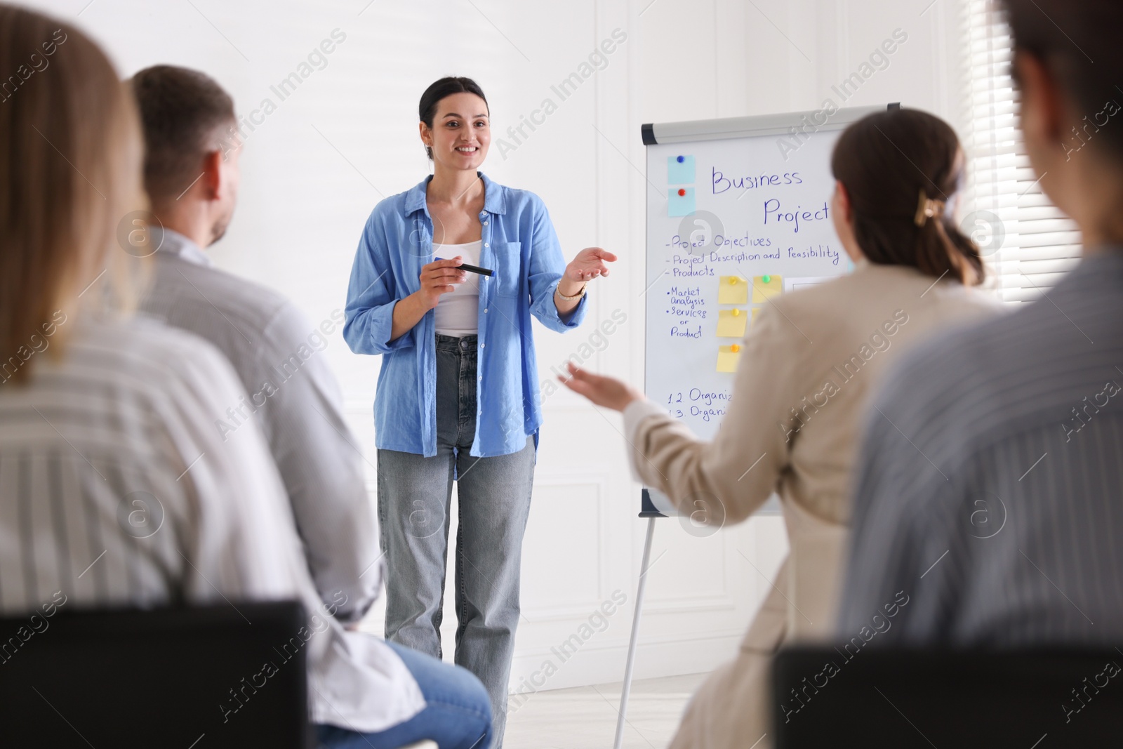 Woman giving public speech in front of audience indoors Photo of Woman giving public speech in front of audience indoors