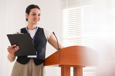 Photo of Woman giving public speech with microphone at lectern indoors