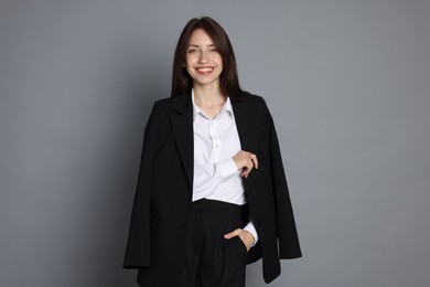 Photo of Happy woman in suit on grey background