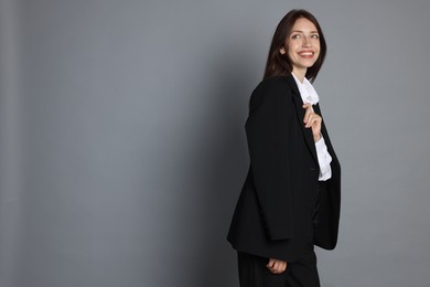 Photo of Happy woman in suit on grey background, space for text